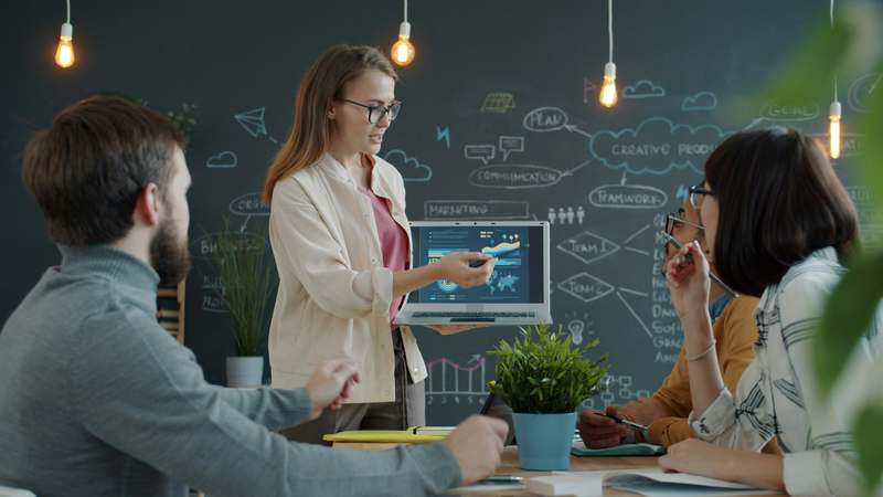 Overhead view of a modern laptop showing a marketing funnel visualization with conversion metrics, surrounded by notebook, coffee cup, and stylus — representing focused digital strategy for online educators